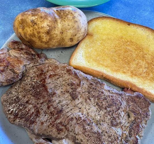 Hamburger steak with a baked potato and garlic bread
